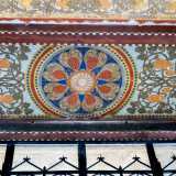 ...e, in un tripudio di colori accesi, un raffinato decoro circolare centrale a forma di rosone con otto grappoli rossi